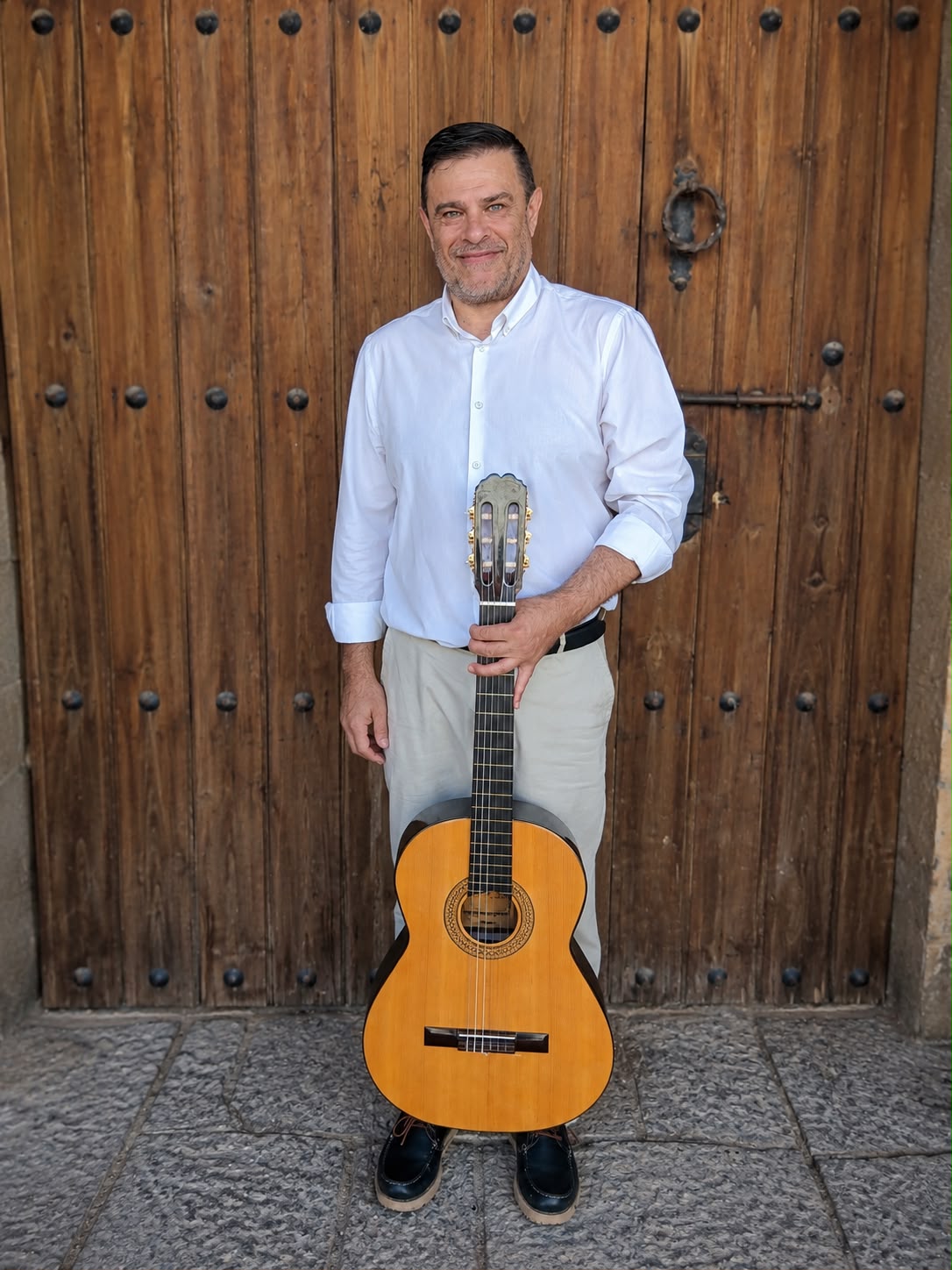 Felipe Sánchez con su guitarra frente a una puerta de madera